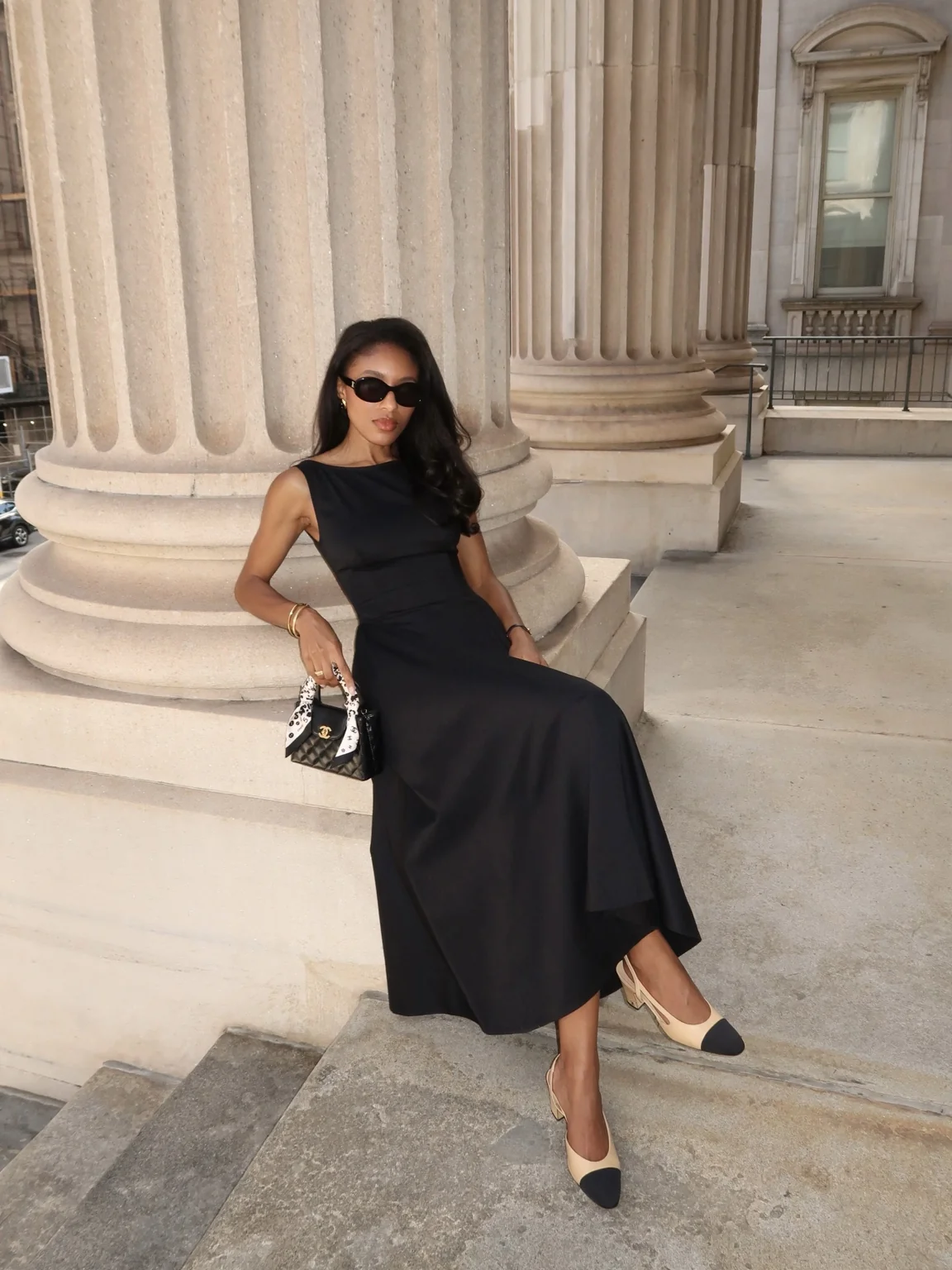 Remonia seated in a black dress and sunglasses